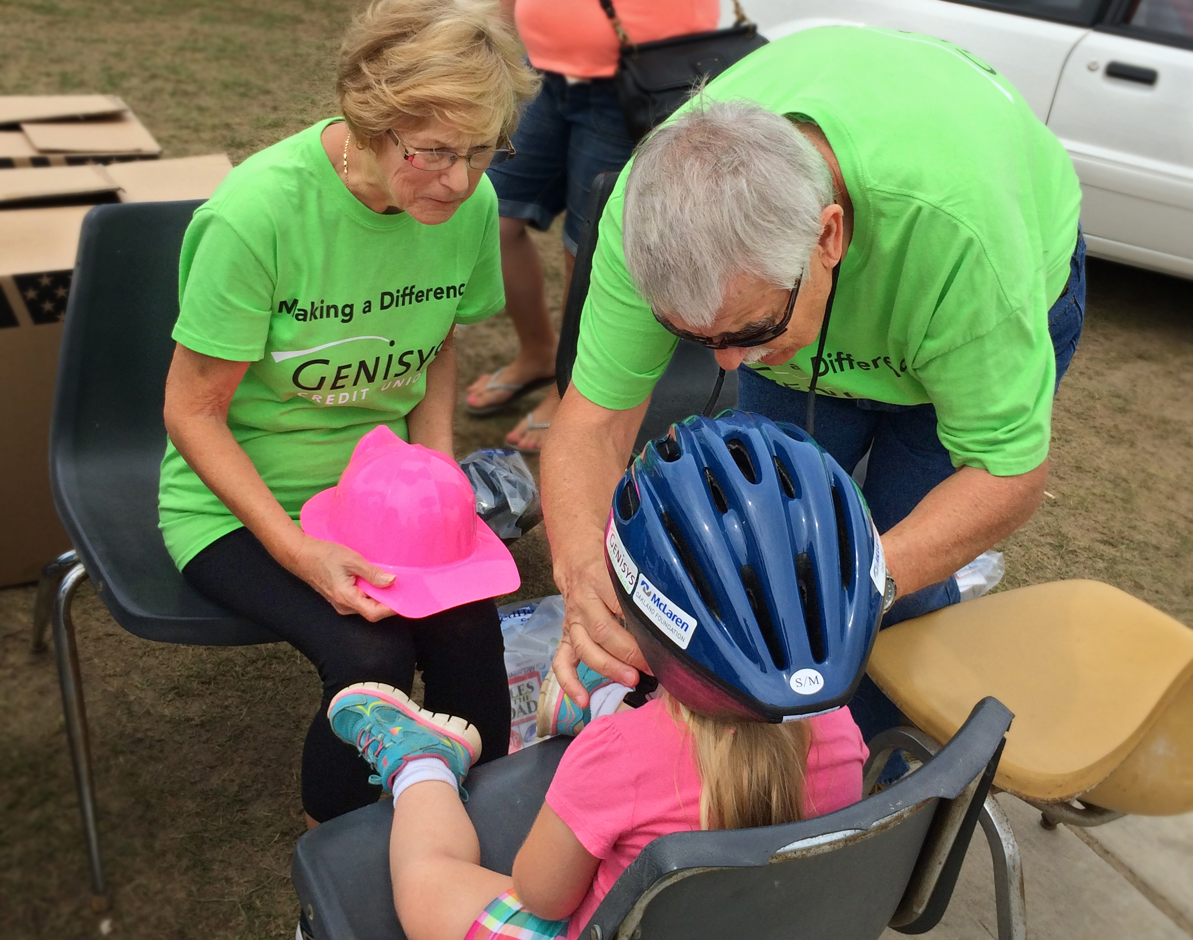 Genisys Volunteers help fit students with helmets